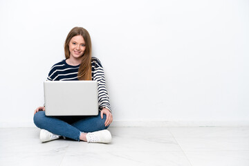 Young caucasian woman with a laptop sitting on the floor isolated on white background laughing