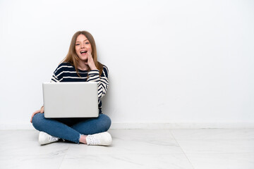 Young caucasian woman with a laptop sitting on the floor isolated on white background with surprise and shocked facial expression