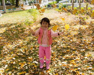 girl playing with dry leaves