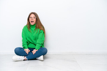 Young caucasian woman sitting on the floor isolated on white background with surprise facial expression