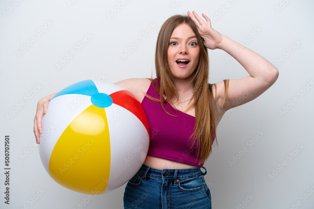 Wall mural Young caucasian woman holding beach ball isolated on white background with surprise expression