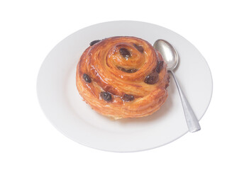 Spiral danish pastry or sweet bun with raisin on top on white plate with small teaspoon served for...