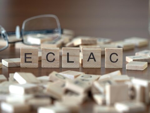 the acronym eclac for economic commission for latin america and the caribbean word or concept represented by wooden letter tiles on a wooden table with glasses and a book