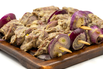 Saslik kebab isolated on white background. Raw saslik kebab on wooden presentation board. close up