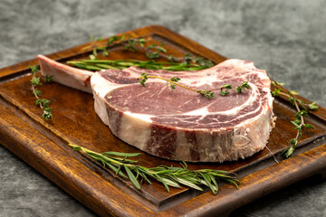 Raw Veal chop on dark background. Raw veal chop on wooden serving board. close up