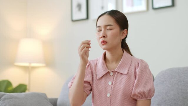 Young Asian woman using rapid antigen test kit (ATK) for self test at home. Pandemic of disease, covid-19, coronavirus