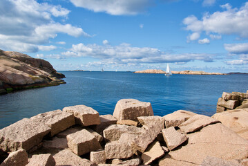 Landscape with a sailing boat on the ocean and red granite rock slabs at St&aring;ngehuvud nature reserve in Bohusl&auml;n in Sweden.