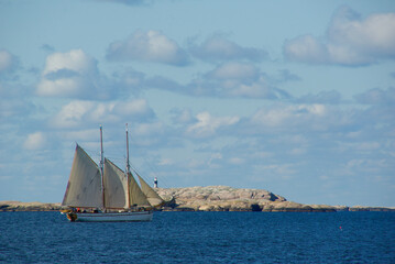 Fototapeta premium Landscape with a sailing ship on the ocean and red granite rock slabs at Stångehuvud nature reserve in Bohuslän in Sweden.