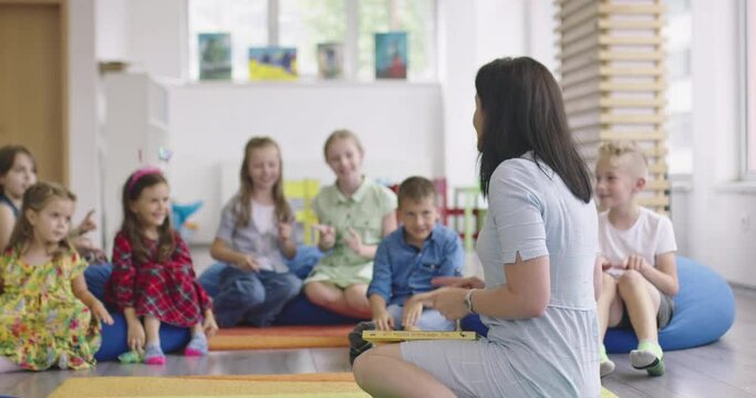 Storytime elementary or primary school teacher reading a story to a group of children in a daycare center. 