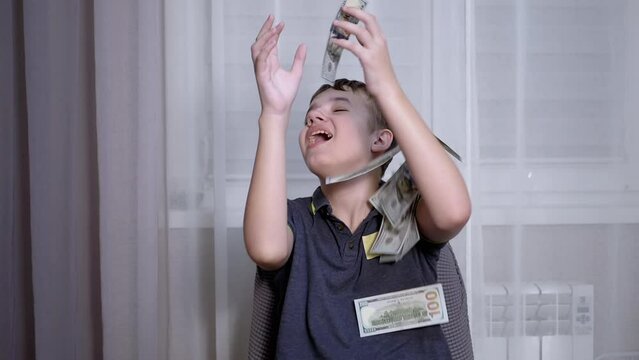 Happy Teenager Catching with Hands Falling 100 Dollar Bills Flying on his Head. Rich successful smiling boy millionaire. Scatter, throw money. Win, fortune. Earnings. Wages. Finance, wealth, capital.