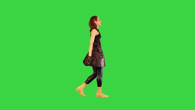 Cyberpunk girl in leather skirt and with gun on belt walks on a Green Screen, Chroma Key.