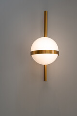 Modern round wall lamp lights bulbs ball shape have a gold metallic centerpiece and a gold bar vertically on wall decoration home and living with space for copy text.