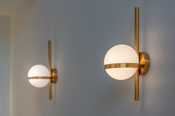 Modern round wall lamp lights bulbs ball shape have a gold metallic centerpiece and a gold bar vertically on wall decoration home and living with space for copy text.