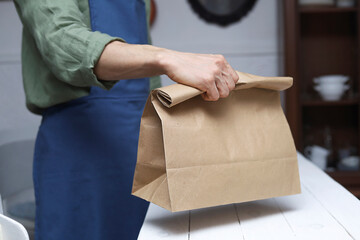 Male hand giving blank paper bag in a zero waste shopn Shop assistant serving customers Mock-up Space for logo or design.