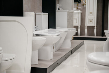 Row of modern new white toilet bowls in a plumbing store.