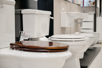 Row of modern new white toilet bowls in a plumbing store.