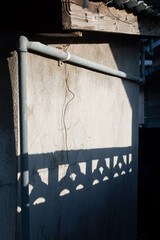 ブロック塀の影が古い建物の壁に投影されている - obrazy, fototapety, plakaty