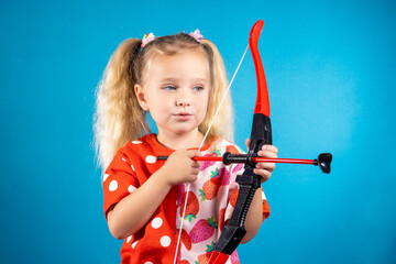 A critical girl in a red dress shoots a bow. The concept of children's games, striving for a goal,...