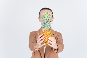 Obraz premium Close-up of hands with ripe honey pineapple. Unrecognizable woman in a beige jacket. Copy space on both sides of the banner.