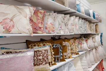 A row of colorful pillows on a shelf in a textile store.