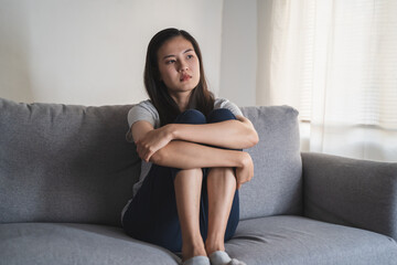 Asian woman covering her face feeling lonely and depressed sit on sofa in the room