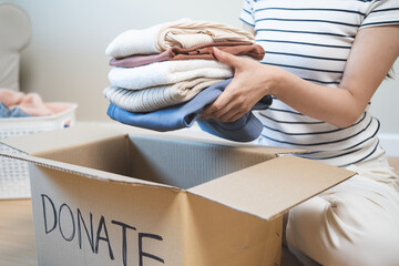 person separate clothes for donation into boxes and wait to give to volunteer charity to share to...
