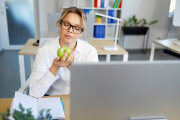 Business woman with green apple in hand at workplace. The concept of good nutrition