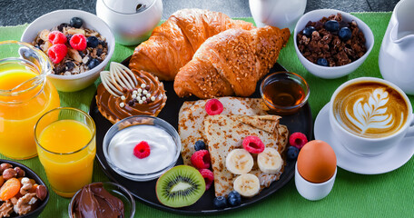 Fototapeta na wymiar Breakfast served with coffee, juice, pancakes and croissants