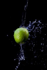 green apple is doused with plenty of water against a black background