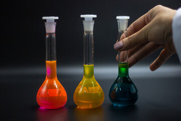 Researcher in the laboratory. Scientific concept.  The researcher held the volumetric flask with green liquid. Chemical test tubes for medical, pharmaceutical and analytical. Hand without gloves. 