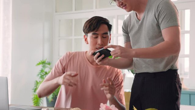 Two handsome Asian men put skin care on backdrop for take a photo product with their smartphone