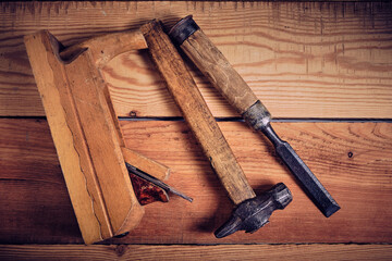 Set of tools for carpenters, hammer, chisel and plane on wooden background.