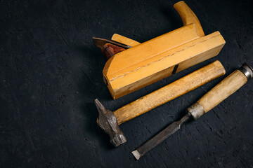 Set of tools for carpenters, hammer, chisel and plane on dark background.
