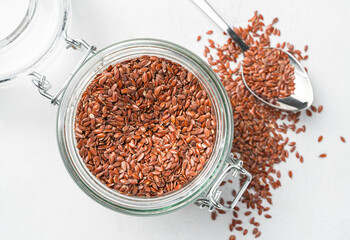 Flax seeds in a transparent jar on a gray background.