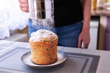 Adding sugar powder onto tasty Easter cake on a plate
