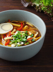Romaine soup. Homemade noodle food. Asian soup with noodles, red pepper, green onion and egg. Copy space. Close up. Healthy food. Traditional Japanese dish. Menu of cafes, restaurants. Wood background