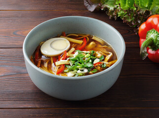 Romaine soup. Homemade noodle food. Asian soup with noodles, red pepper, green onion and egg. Copy space. Close up. Healthy food. Traditional Japanese dish. Menu of cafes, restaurants. Wood background