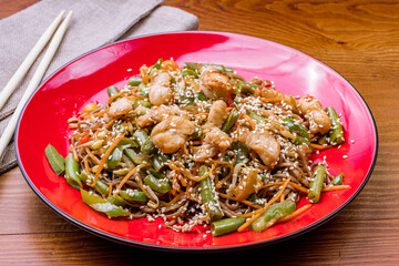 Soba noodles with chicken and vegetables on wooden table