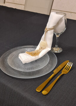 Transparent plate, with napkin and decoration, and gold cutlery
