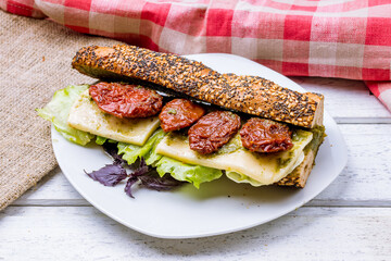 Sandwich with Caprese salad with mozzarella and sun-dried tomato on wooden board