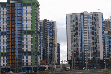 Construction of multi-storey buildings. Modern multi-storey building. Completed and under construction buildings. Construction cranes are visible.