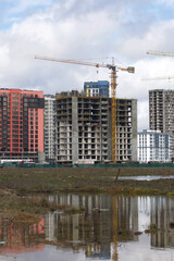 Construction of multi-storey buildings. Modern multi-storey building. Houses with reinforced concrete frame. Work construction cranes.