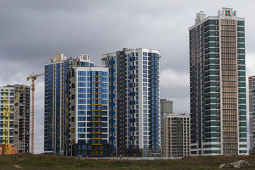 Construction of multi-storey buildings. Modern multi-storey building. Completed and under construction buildings. Construction cranes are visible.