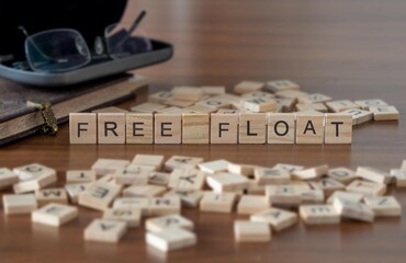 Fototapeta na wymiar free float word or concept represented by wooden letter tiles on a wooden table with glasses and a book