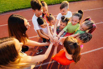 A large group of children, boys and girls, stand together in a circle and fold their hands, tuning...