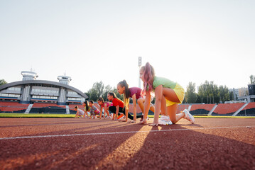 A large group of girls, got ready at the start before running at the stadium during sunset. A...