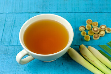 Cup of hot lemongrass tea with sliced and green leaf on blue wooden background. Lemongrass for healthy herbal drink concept.