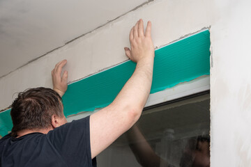 The master installs plastic slopes on windows made of insulated panels covered with a protective...