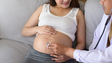 A doctor holding stethoscope is examining a pregnant woman in the hospital , healthcare and pregnancy care concept