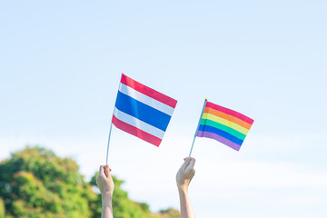 hands showing LGBTQ Rainbow and Thailand flag on nature background. Support Lesbian, Gay, Bisexual,...